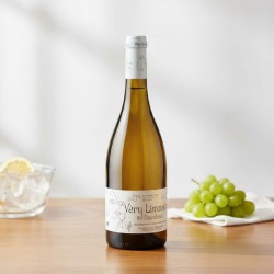 Vin blanc chardonnay. La bouteille repose sur une table en bois clair au grain visible.Un bol en verre rempli de glaçons et d'une tranche de citron suggère la fraîcheur et la préparation d'un service estival.Une belle grappe de raisins verts (raisins de table) est posée sur un linge blanc immaculé, rappelant l'origine du produit.